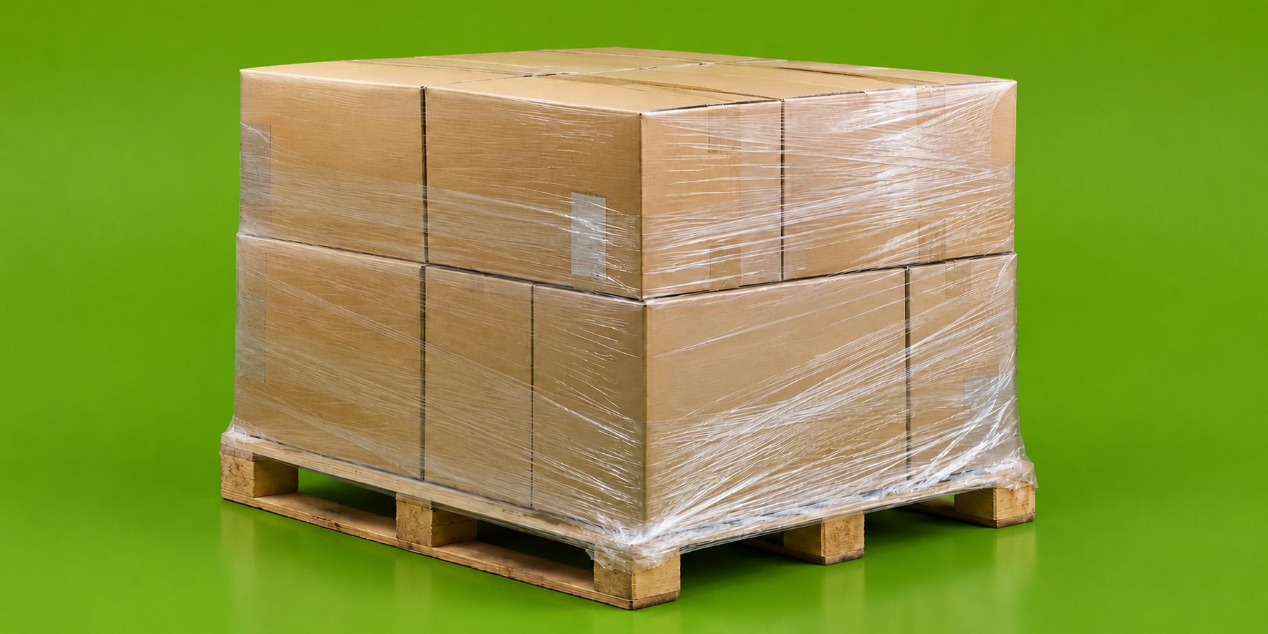Pallet of cardboard boxes wrapped in clear pallet wrap on a green background